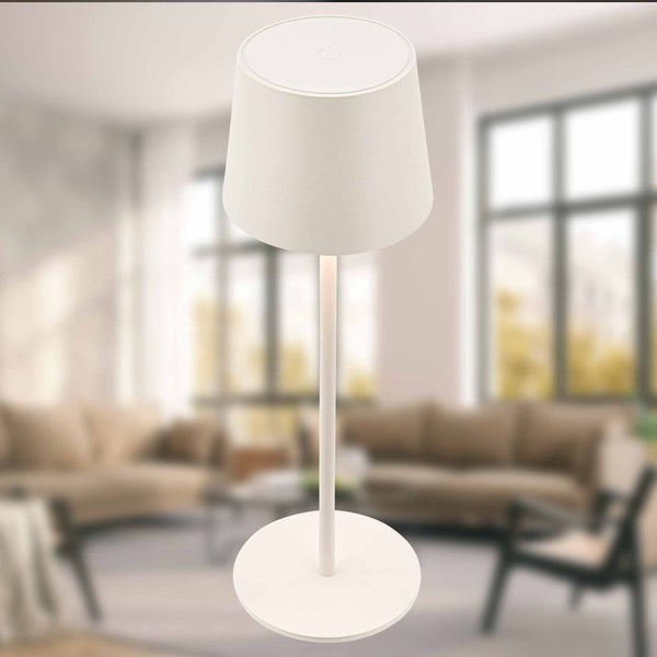 Moderne weiße Tischleuchte mit konischem Schirm und rundem Fuß in einem hellen Wohnzimmer.