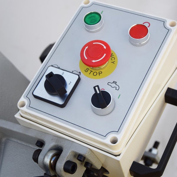 Nahaufnahme eines Bedienfelds mit Schaltern, Knöpfen und Not-Aus-Taste