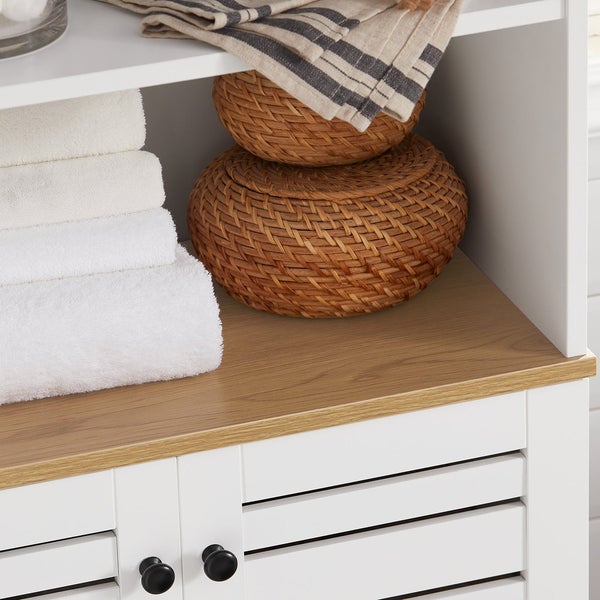Detailansicht eines Badezimmerschranks mit weißen Handtüchern und geflochtenen Körben