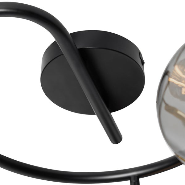 Detailansicht einer schwarzen Leuchte aus Metall mit rundem Wandanschluss und gebogenem Lampenarm.