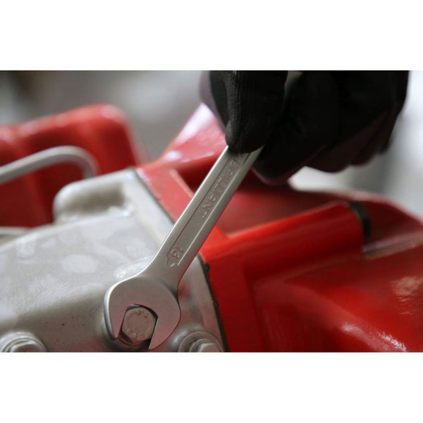 Ein Maulschlüssel der Größe 13 wird von einer Hand mit Handschuh gehalten, um eine Schraube anzuziehen.