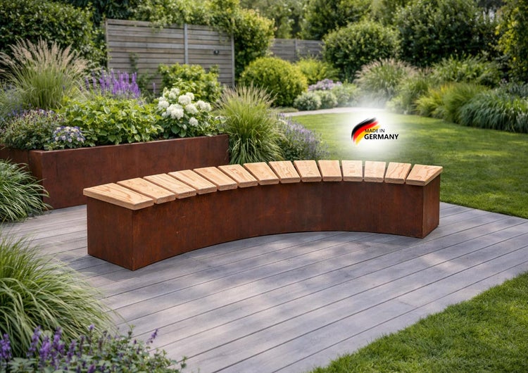 Gebogene Gartenbank aus Cortenstahl mit Sitzfläche aus Holzlatten auf einer Holzterrasse in einem modernen Garten. Hergestellt in Deutschland.