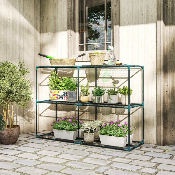 Dreistöckiges Gartenregal aus Metall mit Pflanzen und Blumen vor einer Holzwand auf einem Steinboden.