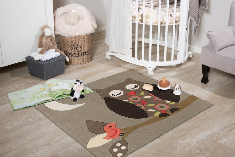 Kinderteppich mit Eulenmotiv in einem hellen Kinderzimmer mit Babybett Spielzeug und Holzoptikboden