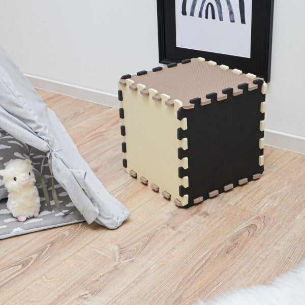 Ein aus ineinandergreifenden Schaumstoff-Spielmatten zusammengesetzter Würfel in einem Kinderzimmer neben einem Tipi.
