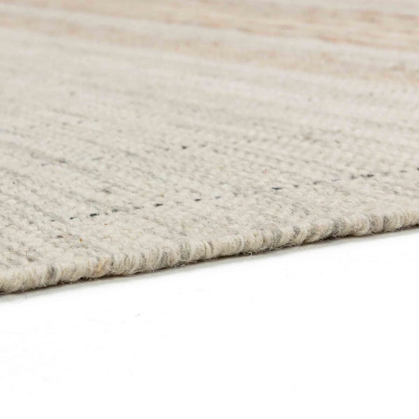 Nahaufnahme eines hellen gewebten Teppichs mit feiner Rippenstruktur und sichtbarer Kante.