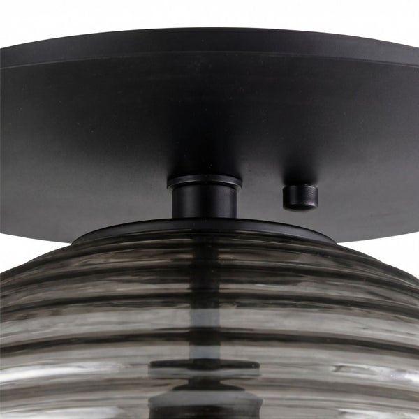 Nahaufnahme einer Deckenleuchte mit schwarzer Metallhalterung und geriffeltem Schirm aus Rauchglas.