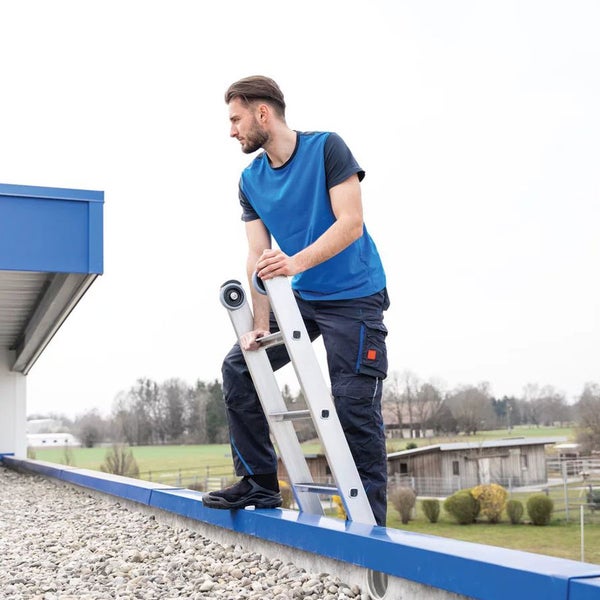 Mann steigt mit einer Anlegeleiter auf ein Dach.