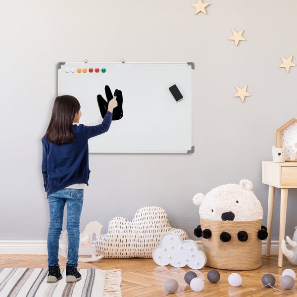 Kind malt auf einem wandmontierten Whiteboard in einem hellen, organisierten Kinderzimmer mit Sternen und Spielzeug.