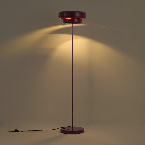 Moderne Stehleuchte mit schmalem Standfuß und zylindrischem Leuchtkopf, der ein warmes Licht nach oben abstrahlt.