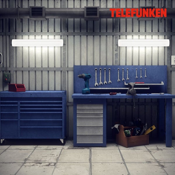 Werkstatt mit zwei hellen Telefunken LED-Lichtleisten über einer blauen Werkbank und einem Werkzeugwagen an einer Metallwand. Telefunken Logo.