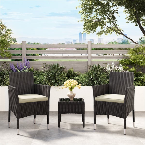 Gartenmöbel-Set aus Polyrattan bestehend aus zwei Sesseln mit Sitzkissen und einem Beistelltisch auf einer Terrasse.