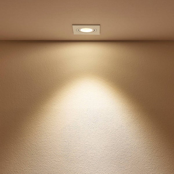 Quadratischer LED-Einbaustrahler an der Decke mit warmweißem Lichtkegel auf einer strukturierten Wand.