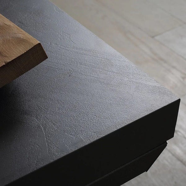 Detailansicht einer schwarzen Tischplatte mit Holzstück