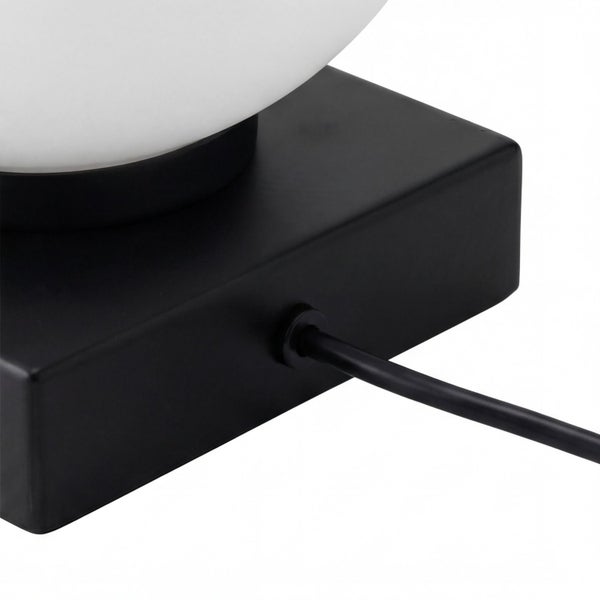 Schwarzer quadratischer Lampenfuß mit Stromkabel und weißem Lampenschirm aus Glas.