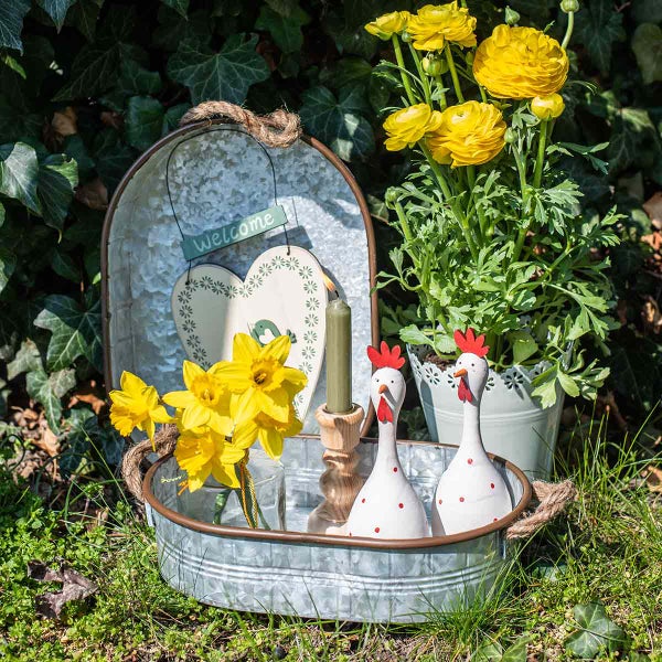 Dekorative Gartenszene mit Tablett, Blumen, Kerze und Hühnerfiguren
