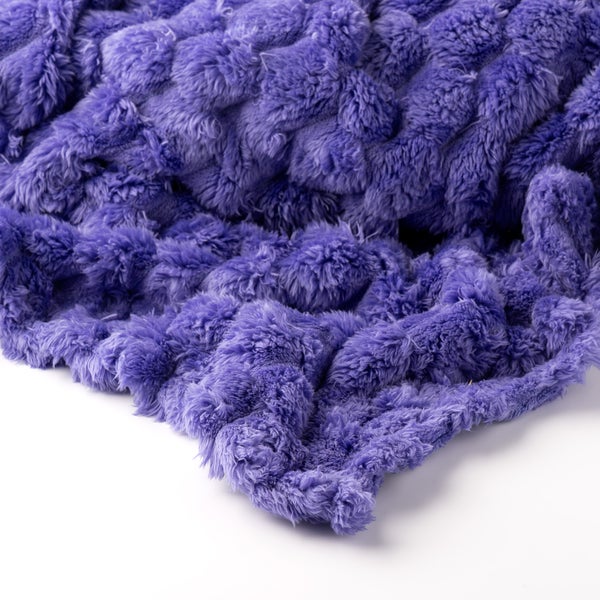 Weiche violette Kuscheldecke aus Kunstfell mit dekorativer Wellenstruktur.