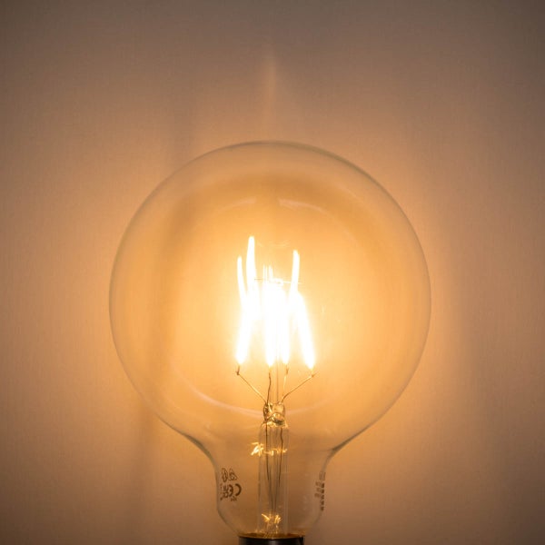 Eingeschaltete runde LED-Filament-Glühbirne Globe-Form aus klarem Glas mit warmem Licht.