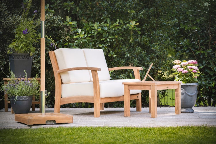 Garten-Lounge-Set aus Holz mit Zweisitzer-Sofa und Beistelltisch auf einer Terrasse vor einer Hecke