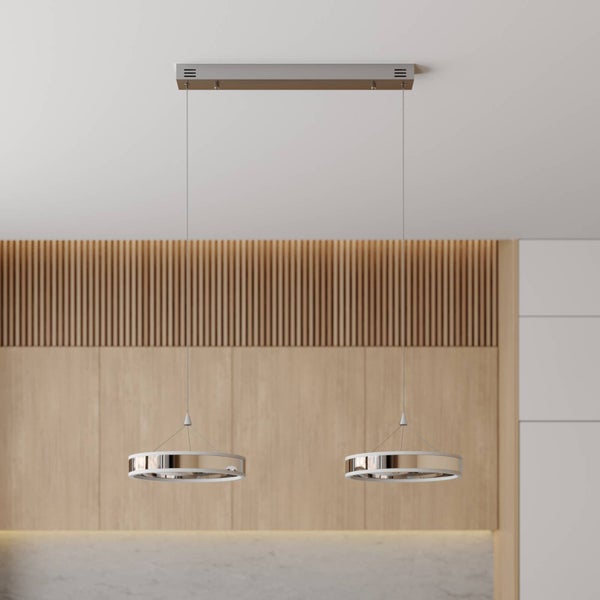 Zweiflammige LED-Pendelleuchte mit kreisförmigen Lichtelementen in Chrom-Optik vor einer modernen Holzwand.