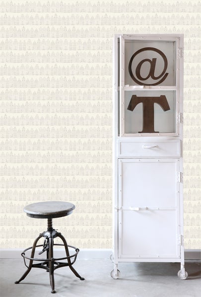 Szene mit einem Hocker, einem weißen Schrank mit Metallakzenten und einer Wand mit einem Muster aus Häusern.