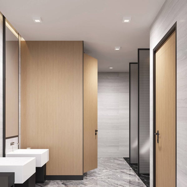 Modernes helles Badezimmer mit weißen Waschbecken, Trennwänden in Holzoptik und grauem Marmorboden.