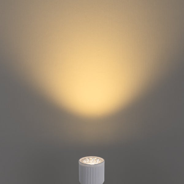 Weißer LED-Strahler mit einem warmweißen Lichtstrahl an einer Wand.