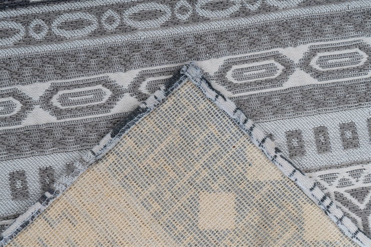 Gewebter Teppich mit geometrischem Muster aus Kreisen und Ovalen, Detailansicht der Rückseite und Kantenverarbeitung.