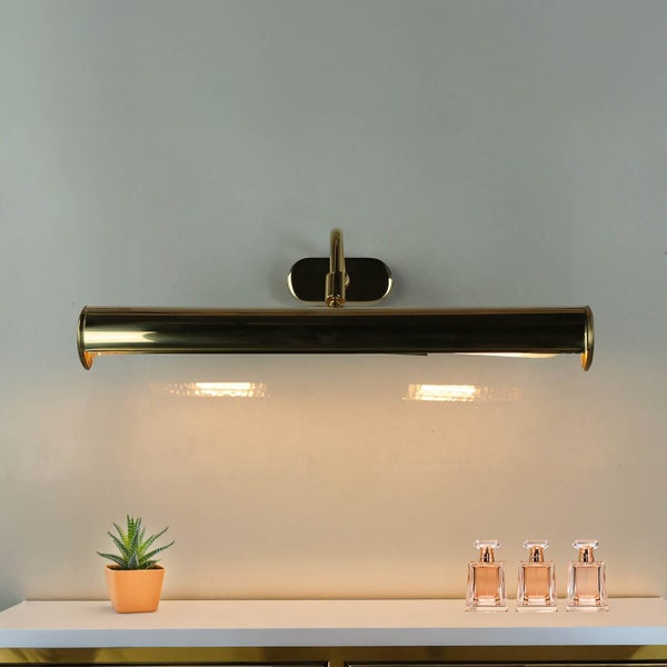 Wandleuchte in Gold über einem Tisch mit Dekorationen.