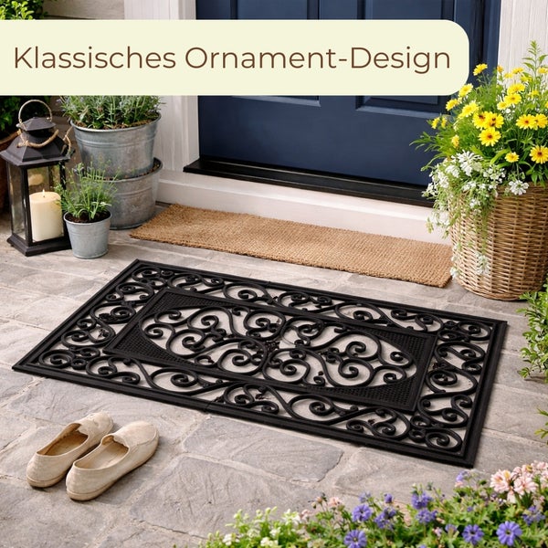 Schwarze Fußmatte mit klassischem Ornamentmuster vor einer Haustür