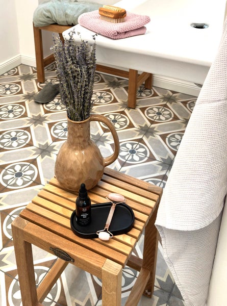 Badezimmer Szene mit Hocker, Dekoration und Badutensilien auf gemusterten Fliesen