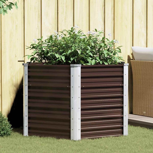 Quadratisches Hochbeet aus gewelltem Metall mit hellen Eckverbindungen, bepflanzt mit blühenden Pflanzen vor einem Holzzaun im Garten.