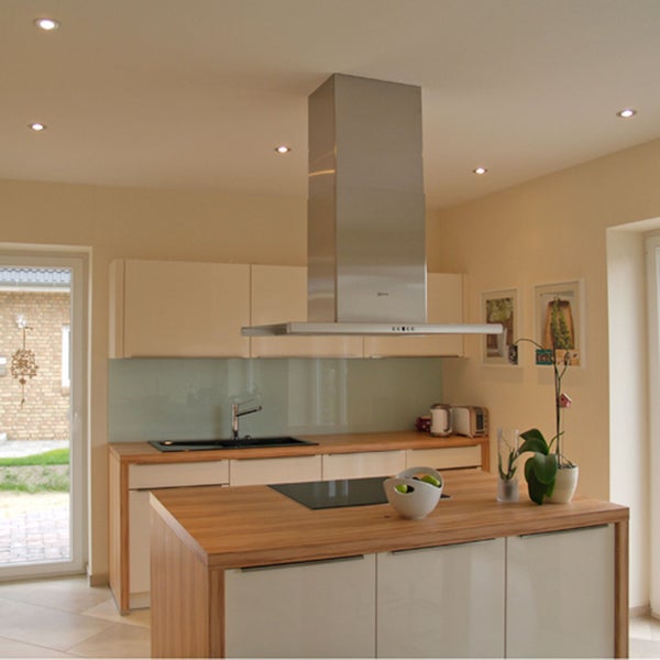 Moderne helle Küche mit Kochinsel, Holzarbeitsplatte, integriertem Kochfeld und einer Dunstabzugshaube aus Edelstahl.