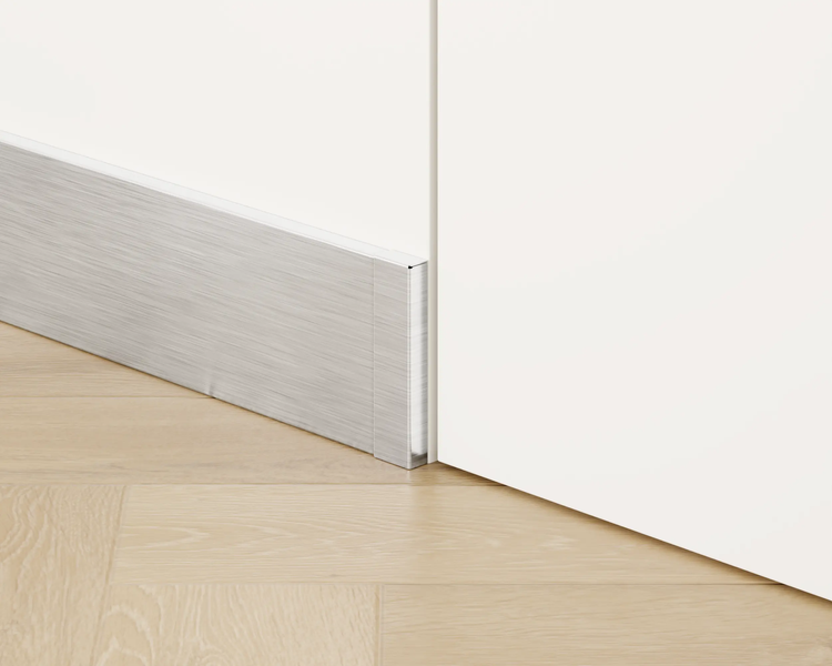 Sockelleiste aus Metall vor einer weißen Wand und einem Holzboden