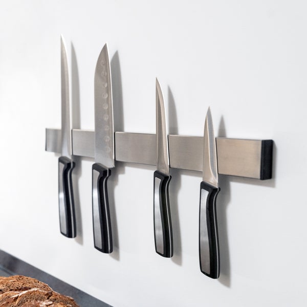 Magnetische Messerleiste aus Edelstahl mit vier Küchenmessern in verschiedenen Größen an einer Wand befestigt.