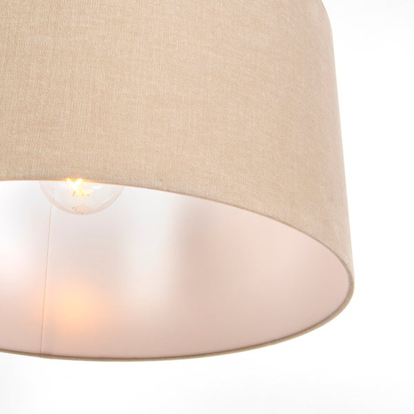 Nahaufnahme eines zylindrischen Lampenschirms aus naturfarbenem Stoff mit eingeschaltetem Leuchtmittel.
