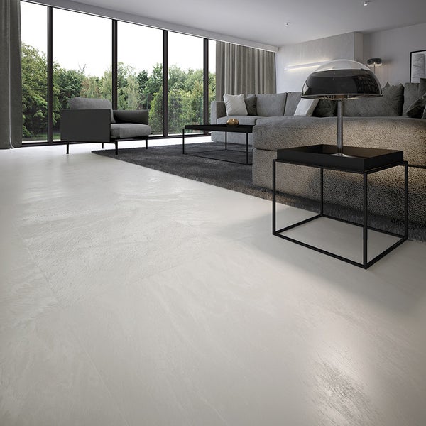 Geräumiges Wohnzimmer mit modernen Fliesenboden in Steinoptik, bodentiefen Fenstern und minimalistischer Einrichtung mit Sofa und Beistelltischen.