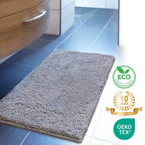 Grauer Badteppich vor einem Badezimmerschrank mit den Siegeln ECO, 10 Jahre Garantie und OEKO-TEX