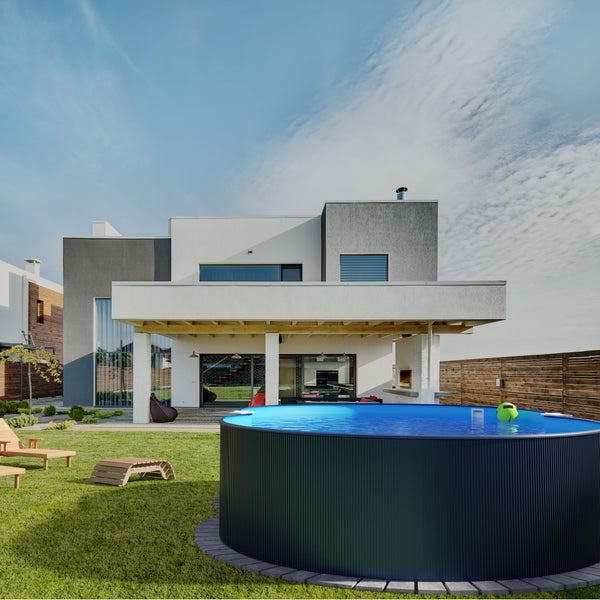 Garten mit rundem Pool, Liegestühlen und modernem Haus