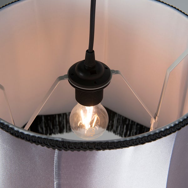 Detailansicht des Inneren eines Lampenschirms mit leuchtender LED-Lampe und dekorativer Borte am unteren Rand.