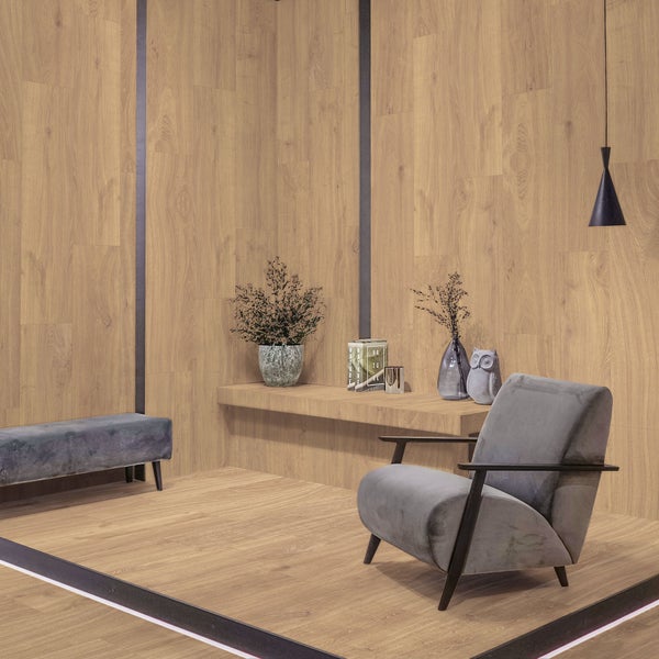 Wohnzimmer mit hellem Laminat in Holzoptik an Boden und Wänden, grauem Sessel, Bank und Dekoration.