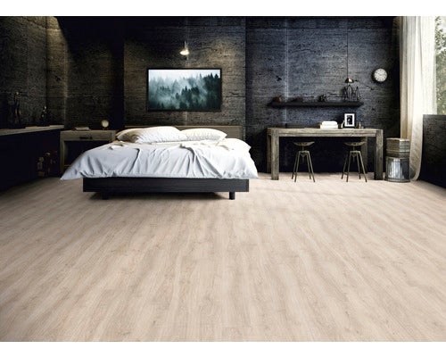 Schlafzimmer mit hellem Holzboden, Bett und Schreibtisch.