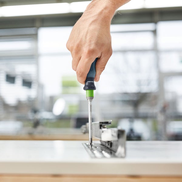 Hand schraubt Schraube mit Schraubendreher ein