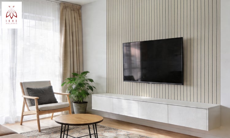 Modernes helles Wohnzimmer mit vertikalen Wandpaneelen aus Holz, wandmontiertem Fernseher, schwebendem Lowboard, Sessel und Couchtisch. IKHE MALARKA Logo.