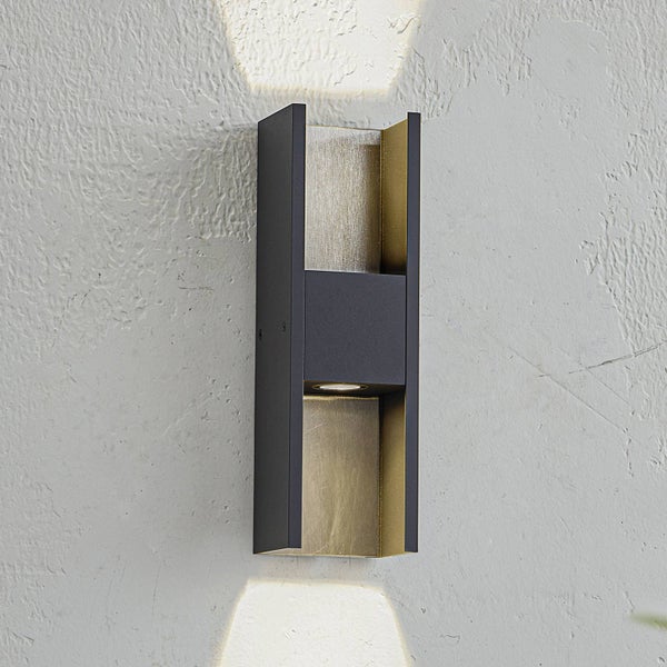 Moderne rechteckige Wandleuchte in Schwarz mit goldener Innenseite, Licht nach oben und unten an einer strukturierten Wand.