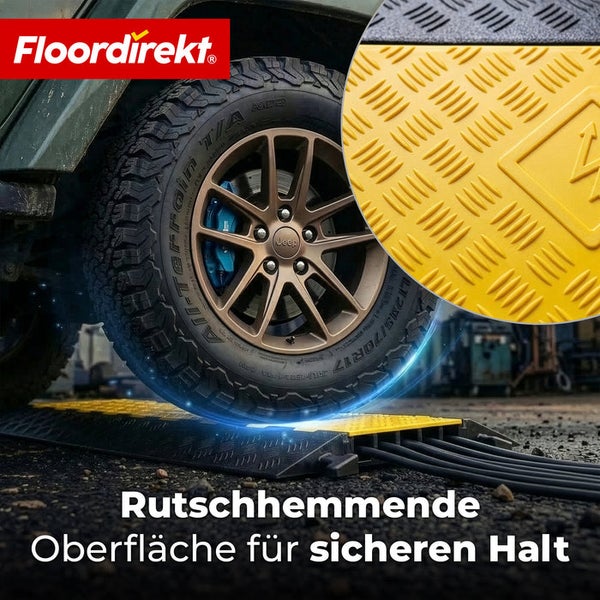 Floordirekt Logo. Robuste Kabelbrücke mit rutschhemmender Oberfläche, über die ein Reifen fährt. Kabel verlaufen durch interne Kanäle.