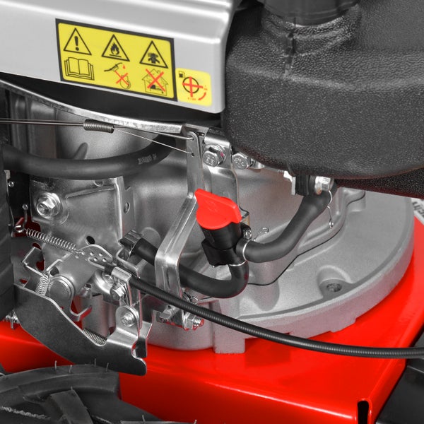 Detailaufnahme eines Rasenmähermotors mit Warnhinweisen, rotem Benzinhahn und schwarzen Kabeln.