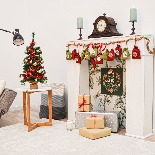 Weihnachtlich dekorierter Kaminumbau mit Adventskalender aus kleinen Stoffbeuteln und Geschenken.