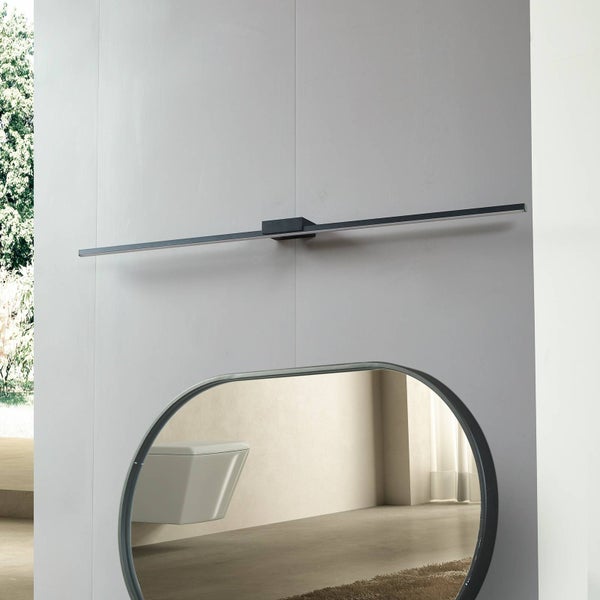 Moderne schwarze LED-Wandleuchte über einem ovalen Spiegel in einem hellen, minimalistischen Badezimmer.