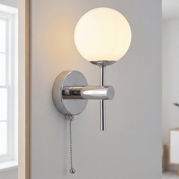 Moderne Wandleuchte mit kugelförmigem Glasschirm und Zugschalter montiert an einer Wand